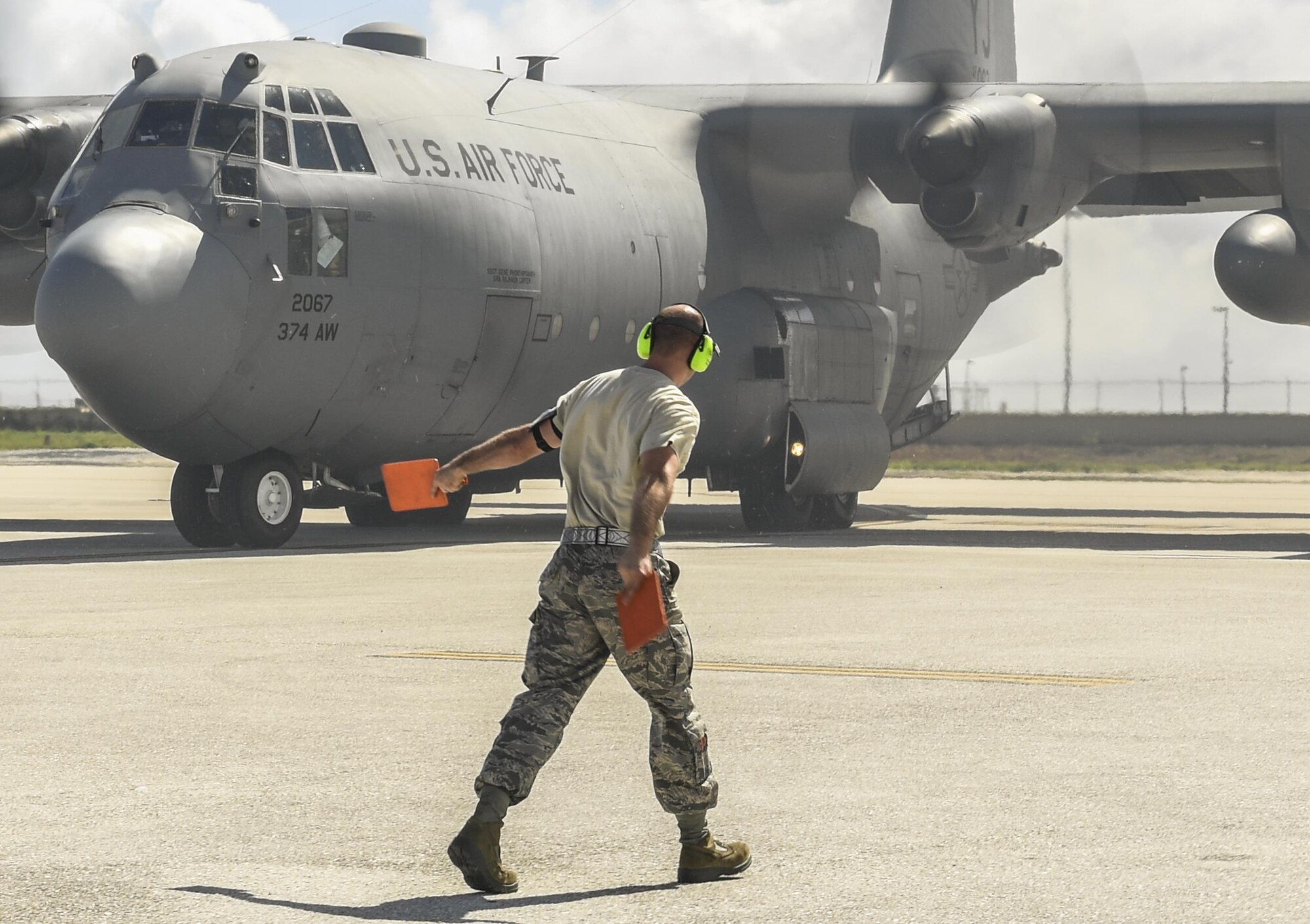 Staff Sgt. Solomon Faulkner, 374th Maintenance Group aerospace ground equipment craftsman, marshals a C-130H Hercules for takeoff during Operation Christmas Drop 2016 at Andersen Air Force Base, Dec. 7, 2015. During OCD, members of various maintenance shops functioned as a team and adapted to duties they would not ordinarily perform in order to meet the needs of the mission. (U.S. Air Force photo by Senior Airman Elizabeth Baker/Released)