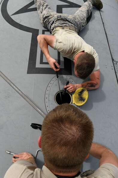 Senior Airman Benjamin Campanella, top, 374th Maintenance Group crew chief, and Staff Sgt. Andrew Thompson, 374 MXG craftsman, work as quickly as they can to repair a hydraulic leak in a C-130H Hercules wing during Operation Christmas Drop 2016 at Andersen Air Force Base, Dec. 7, 2015. When the engine on one aircraft malfunctioned, the 374 MXG team worked together to prepare a spare plane for flight within two hours, enabling the air crew to finish their mission for the day. (U.S. Air Force photo by Senior Airman Elizabeth Baker/Released)