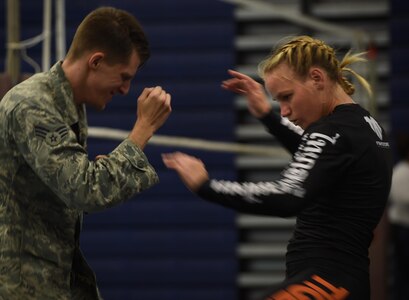 U.S. Air Force Senior Airman Ryan Hooper, 633rd Security Forces Squadron base defense operations center controller, trains with Valentina Shevchenko, UFC Bantamweight fighter, at Joint Base Langley-Eustis, Va., Dec. 8, 2016. Shevchenko not only trained with Airmen, but also visited JBLE units throughout the week as part of a military appreciation visit. (U.S. Air Force photo by Staff Sgt. Natasha Stannard)
