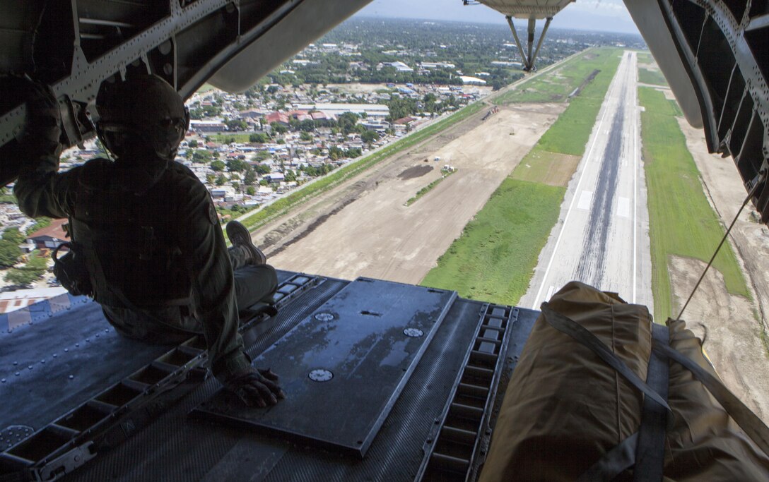 U.S. Marine Staff Sgt. Adam Stanley, CH-53E Super Stallion helicopter crew chief, rides on the rear ramp during takeoff from Port-au-Prince International Airport to deliver goods to the areas affected by Hurricane Matthew, October 15, 2016. After 8 days of supply drop operations; Joint Task Force Matthew has delivered over 217 metric tons of supplies utilizing CH-53E Super Stallion and CH-47 Chinook helicopters. JTF Matthew, a U.S. Southern Command-directed team comprised of Marines, soldiers, sailors and airmen, is providing critical airlift capabilities during the initial stages of the U.S. Agency for International Development's disaster relief operations in Haiti while the international response builds. (U.S. Marine Corps photo by Sgt. Adwin Esters/Released)