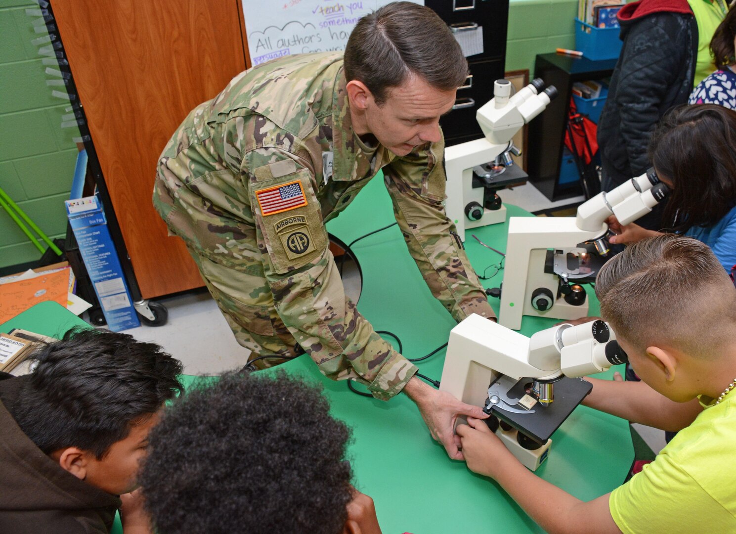 Lt. Col. Werner J. Barden, 264th Medical Battalion commander at Joint Base San Antonio-Fort Sam Houston, assists students viewing bacterial and pathogens under a medical microscope.