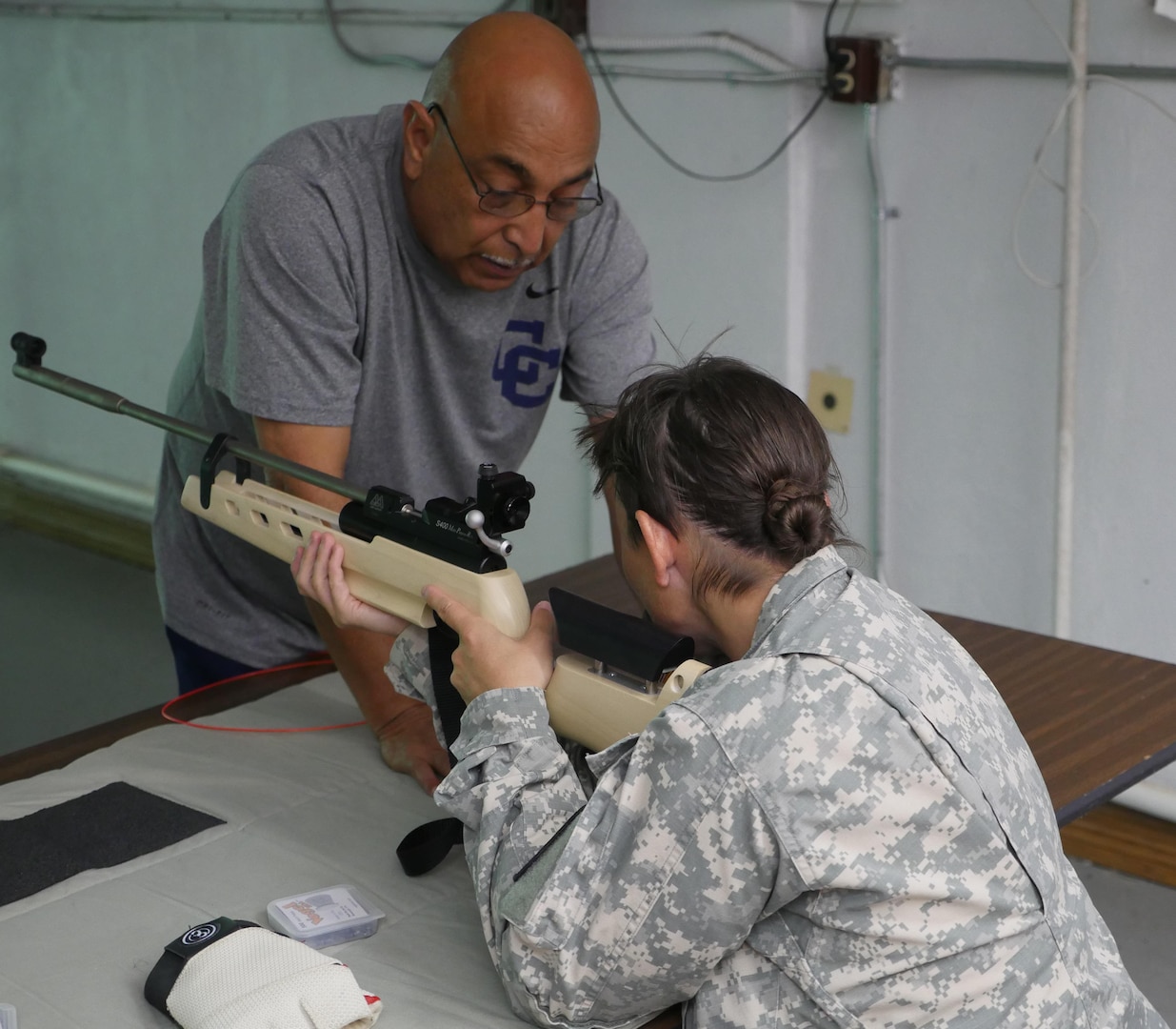 U.S. Army Retired 1st Sgt. Pete Carrion, Army JROTC instructor at Central Catholic High School, San Antonio, Texas, offers shooting tips to Staff Sgt. Tiffany Rodriguez-Rexroad, Bravo Company, Warrior Transition Battalion, Brooke Army Medical Center, during an air rifle training session at Central Catholic High School, San Antonio, Texas, Nov. 10, 2016. The training is part of the WTB’s adaptive reconditioning program. (U.S. Army photo by Robert A. Whetstone/Released)