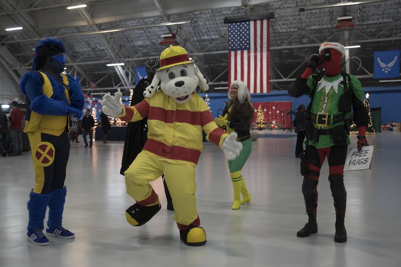 Sparky the Fire Dog, National Fire Protection Association, dances with volunteers dressed as popular superhero characters during the 2016 Parents and Children Fighting Cancer Christmas Party at Joint Base Andrews, Md., Dec. 10, 2016. Hangar 3 was transformed into a winter wonderland-theme for approximately 45 military families to enjoy refreshments, performances and spend time with their favorite superhero and princess characters. Santa and Mrs. Claus also stopped by to deliver presents to the attending families. (U.S. Air Force photo by Airman 1st Class Rustie Kramer)