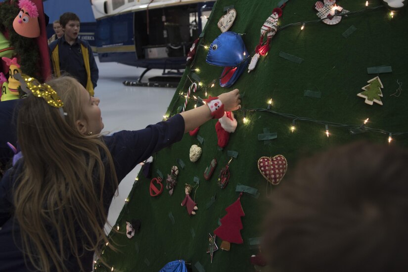 Children decorate a holiday tree with ornaments during the 2016 Parents and Children Fighting Cancer Christmas Party at Joint Base Andrews, Md., Dec. 10, 2016. The tree was later used in a puppet show performed by the Berryville Baptist Rascals.  The JBA Fisher House has sponsored the event for 29 years. (U.S. Air Force photo by Airman 1st Class Rustie Kramer)
