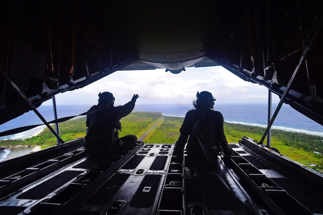 Air Force airmen look out the back of a C-130 Hercules over the Micronesian islands during Operation Christmas Drop, Dec. 6, 2016. Air Force photo by Senior Airman Delano Scott 