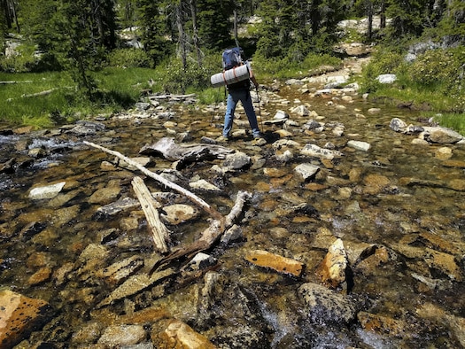 Wes Evans, an experienced mountaineer, carefully fords an alpine runnoff in the Sawtooth National Forest, Idaho, December 16, 2016. Wide shallow, creeks are common in the valleys between mountains and often require quick thinking to get across.(U.S. Air Force photo by Senior Airman Connor J. Marth/Released)