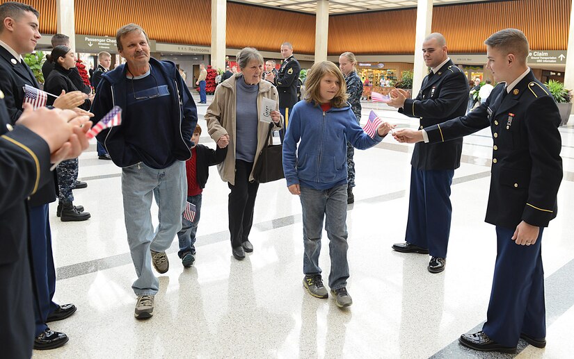 U.S. service members hand U.S. flags to Gold Star families as they leave for the Snowball Express at Norfolk International Airport, Norfolk, Va., Dec. 11, 2016. Gold Star families traveled to Dallas on a four-day, all expenses paid trip to thank them for their family member’s sacrifice. (U.S. Air Force photo by Staff Sgt. Teresa J. Cleveland)
