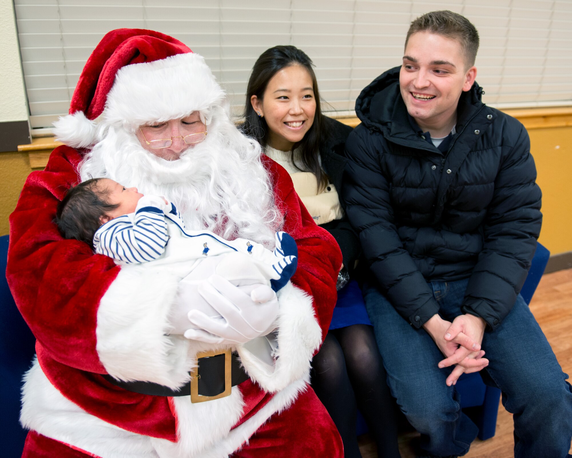 Staff Sgt. Brian Nix (right), 60th medical Support Squadron, watches as his newborn son Hiro visits with Santa Claus for the first time during the annual holiday tree lighting ceremony at Travis Air Force Base, Calif., Dec. 8, 2016. Patrons were treated to music by the U.S. Air Force Band of the Golden West Quartet, a visit from Santa and refreshments. (U.S. Air Force photo/Louis Briscese)