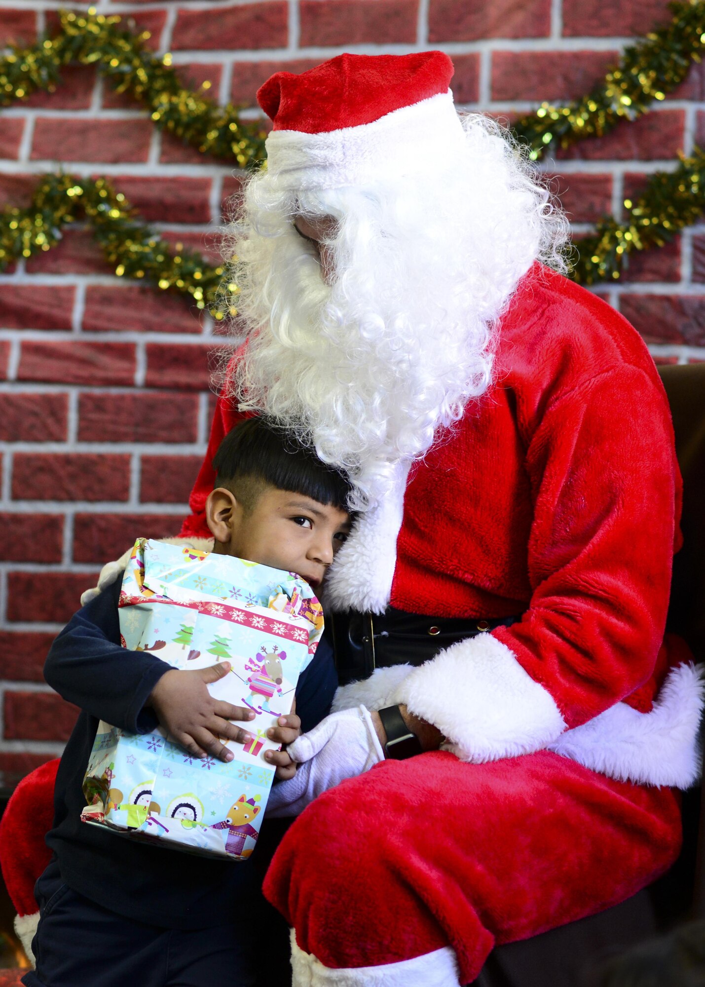 Santa Claus hugs a student during the Santa’s in Blue event at San Xavier Mission School in Tucson, Ariz., Dec. 13, 2016. This year, Santa delivered gifts donated by D-M Airmen to more than 1,000 students at four different schools in the Tucson area. (U.S. Air Force photo by Airman Nathan H. Barbour)
