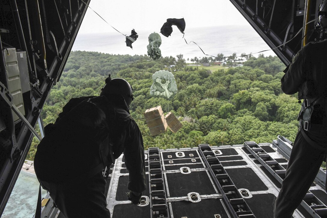 Air Force Staff Sgt. Andrew Thompson and Airman 1st Class Alejandra Vargas push boxes of gifts off a C-130 Hercules during Operation Christmas Drop over an island in Micronesia, Dec. 8, 2016. This year marks 65 years of Operation Christmas Drop, a humanitarian airlift operation that provides airlift training opportunities for peace and wartime efforts. Air Force photo by Airman 1st Class Jacob Skovo