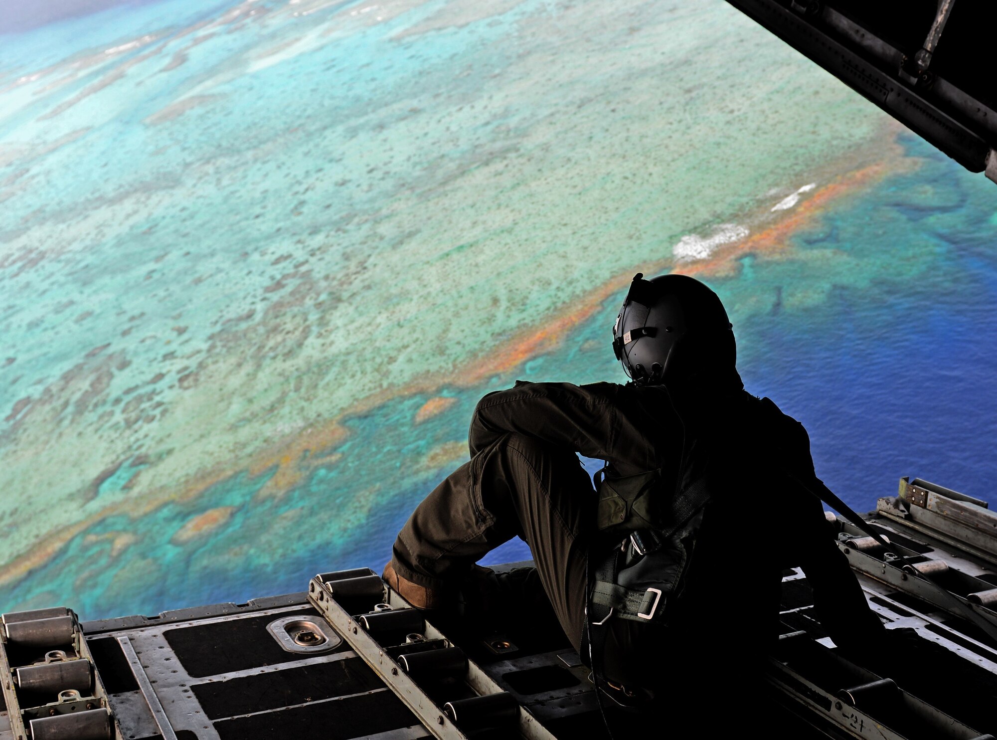 Senior Airman Angel Torres, a loadmaster from the 36th Airlift Squadron, Yokota Air Base, Japan, sits on the back of a C-130 Hercules during Operation Christmas Drop Dec. 8, 2016, over the Pacific Ocean. Sixty-Five years in the making, Operation Christmas Drop is the longest-running humanitarian airlift operation in the Department of Defense. (U.S. Air Force photo by Airman 1st Class Gerald Willis)