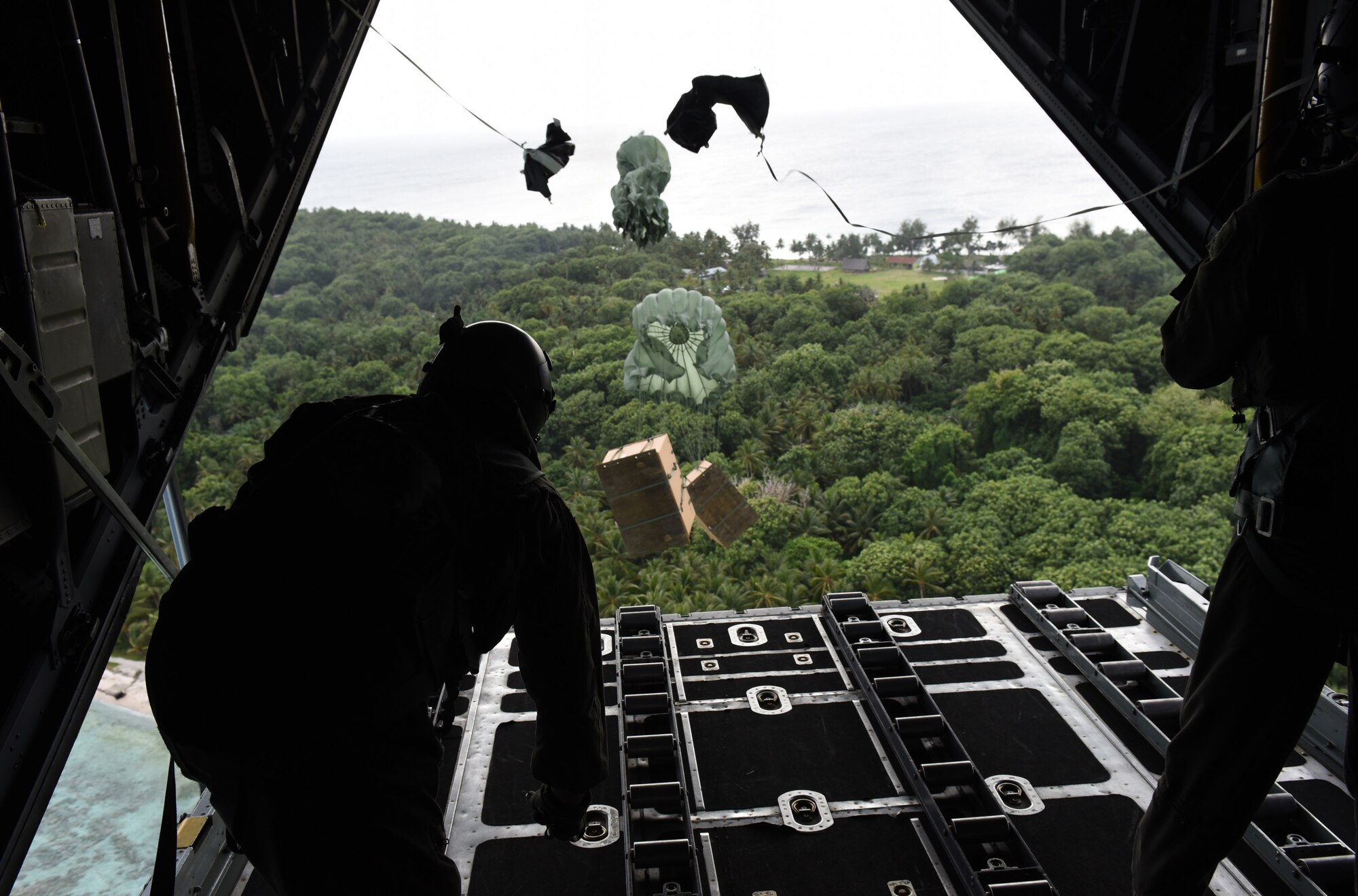 Staff Sgt. Andrew Thompson and Airman 1st Class Alejandra Vargas, loadmasters from the 36th Airlift Squadron, Yokota Air Base, Japan, push boxes of gifts off a C-130 Hercules over a remote Micronesian island during Operation Christmas Drop  Dec. 8, 2016. This year marks 65 years of Operation Christmas Drop, a humanitarian airlift operation, which provides joint airlift training opportunities for both peace and wartime efforts. (U.S. Air Force photo by Airman 1st Class Jacob Skovo)