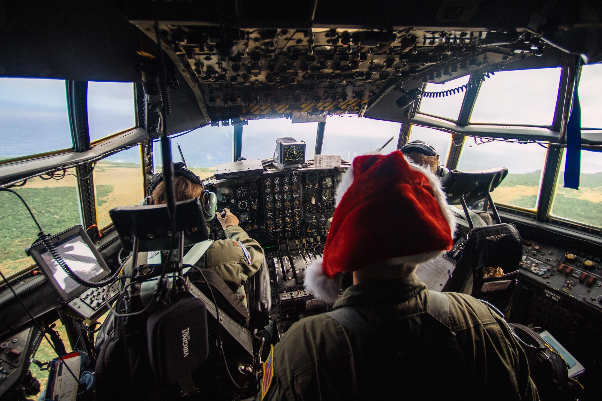 Crewmembers of a C-130 Hercules assigned to the 36th Airlift Squadron fly over remote a Micronesian island during Operation Christmas Drop 2016, Dec. 5, 2016. This year marks the 65th year of Operation Christmas Drop, which began in 1952, making it the world's longest-running airdrop mission. (U.S. Air Force photo by Senior Airman Delano Scott/Released)