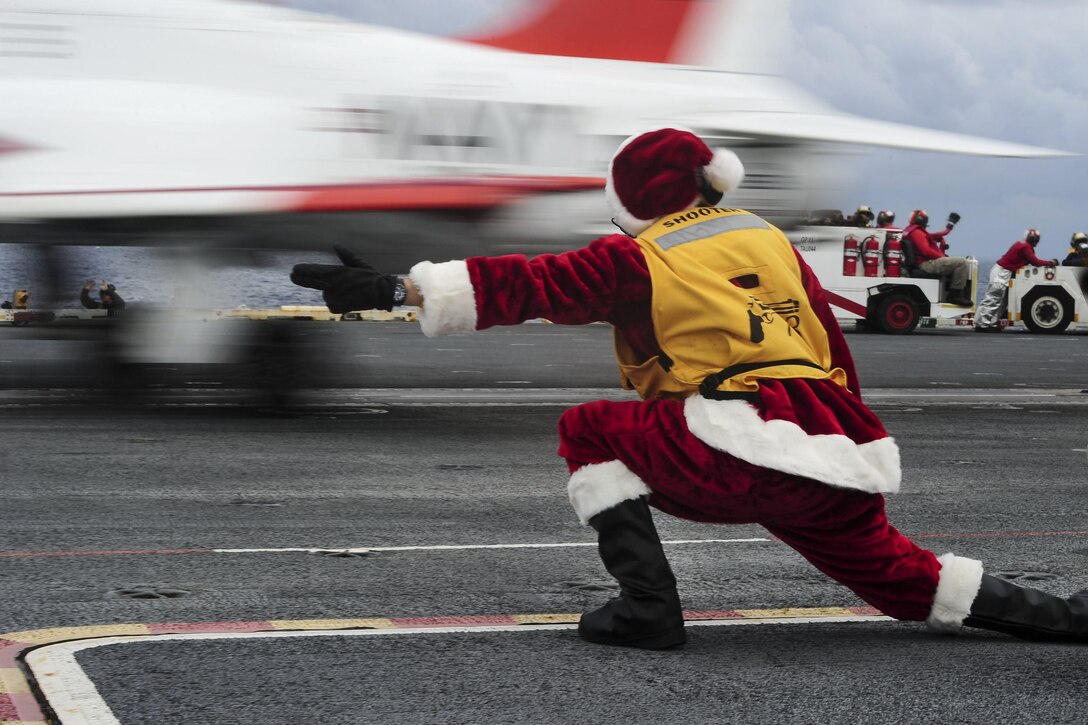 A sailor dressed as Santa Claus gives the signal to launch a T-45C Goshawk from on the flight deck of the aircraft carrier USS George Washington in the Atlantic Ocean, Dec. 10, 2016. The ship is conducting carrier qualifications. Navy photo by Petty Officer 3rd Class Wyatt L. Anthony