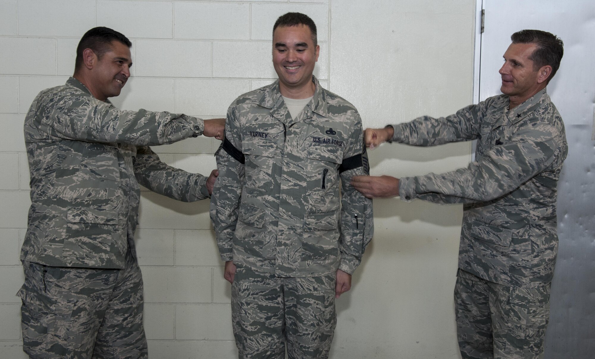 U.S. Air Force Brig. Gen. Barry Cornish, right, 18th Wing commander and Lt. Col. Pete Leija, left, 18th Equipment Maintenance Squadron commander, tack on the rank of chief master sergeant to Senior Master Sgt. Michale Varney, 18th EMS armament flight chief Dec. 8, 2016, at Kadena Air Base, Japan. Tacking on rank is a time-honored tradition in the Air Force symbolizing promotion. (U.S. Air Force photo by Senior Airman Lynette M. Rolen/Released)