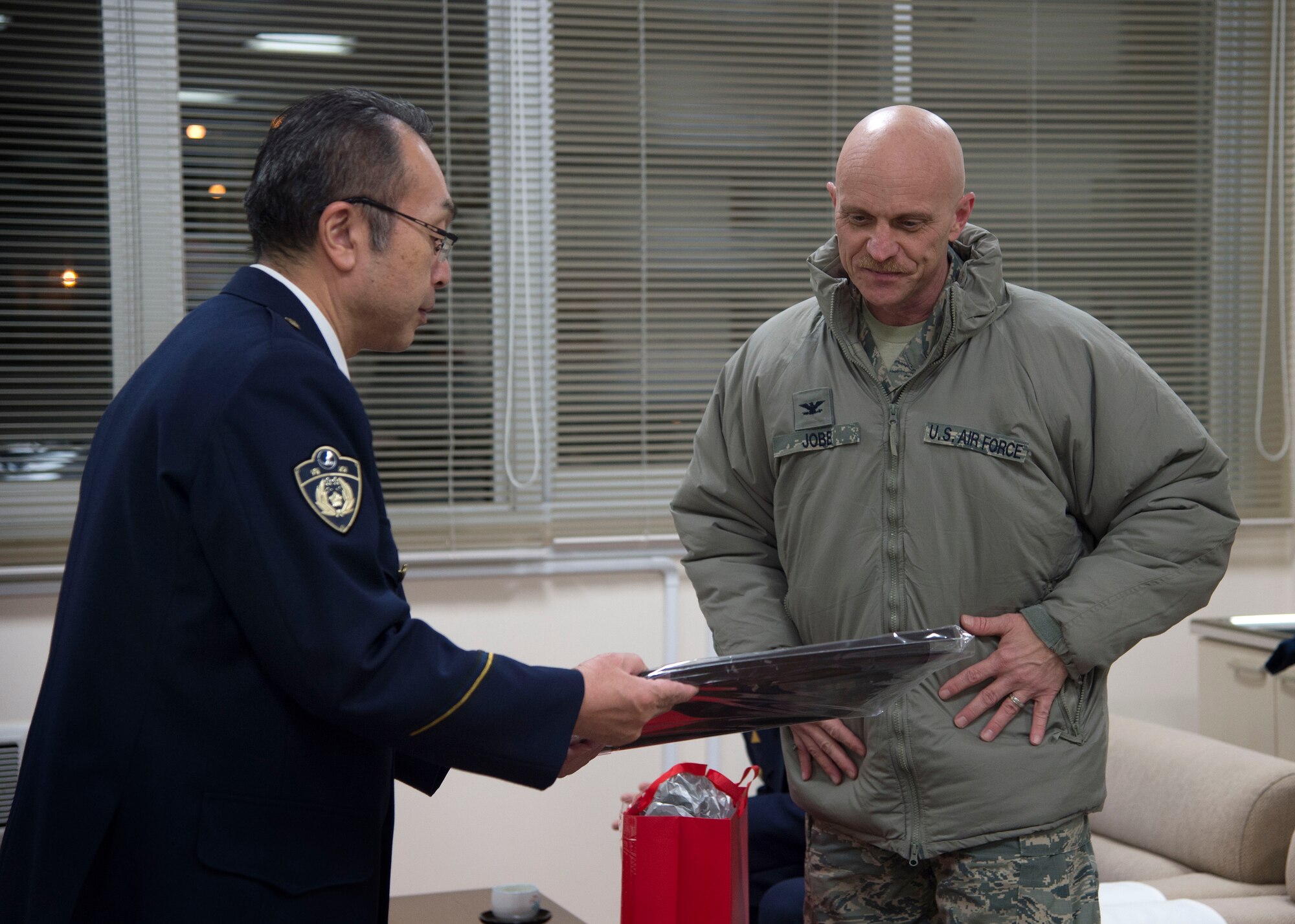 U.S. Air Force Col. R. Scott Jobe, right, the 35th Fighter Wing commander, presents his personal artwork as a gift to Katsuji Soma, left, Misawa City police station chief, during the End-Of-Year Traffic Safety and Crime Prevention Campaign in Misawa City, Japan, Dec. 14, 2016. This annual event showcases safety within the community of Misawa and combats crimes, alcohol related incidents, fraud and traffic accidents during the holiday season. (U.S. Air Force photo by Senior Airman Deana Heitzman)