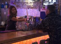 U.S. Navy Capt. Keith Henry, Naval Air Facility Misawa commanding officer, hands a flag with emergency services phone numbers to a local business worker in Misawa City, Japan, Dec. 14, 2016. After opening ceremonies, base, town and local police leadership went to three local eating establishments to present the right tools if they encounter a suspicious person or see suspicious activity around their work place. (U.S. Air Force photo by Senior Airman Deana Heitzman)