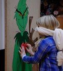 Caroline Campbell, daughter of Lt. Col. Jason Campbell, 39th Expeditionary Mission Support Group deputy commander, pins a heart on the Grinch during the second annual Elf Bootcamp at Ramstein Air Base, Germany, Dec. 12, 2016. Stations at the holiday celebration included a bounce house, a snow machine, and pin the heart on the Grinch.  (U.S. Air Force photo by Airman 1st Class Savannah L. Waters)