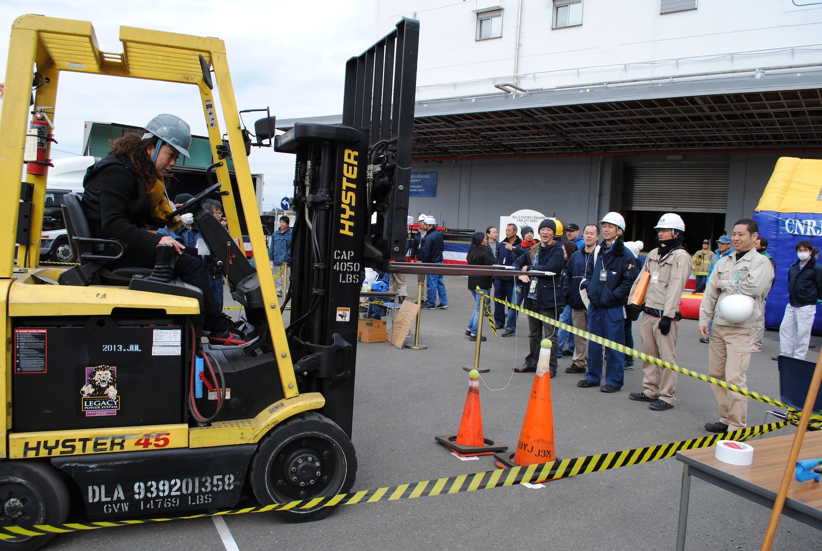 An employee works to land a tennis ball on a traffic cone, demonstrating precise equipment handling, during one of the events at the DLA Distribution Yokosuka, Japan, Forklift Rodeo.