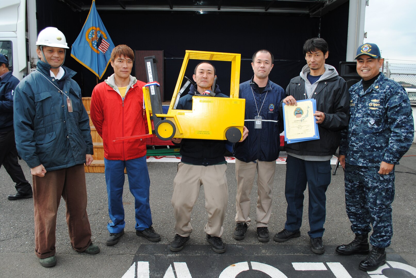 Navy Cmdr. Nolasco Villanueva, commander of DLA Distribution Yokosuka, Japan, presents the first place Forklift Rodeo trophy to the distribution center’s Transportation Division.