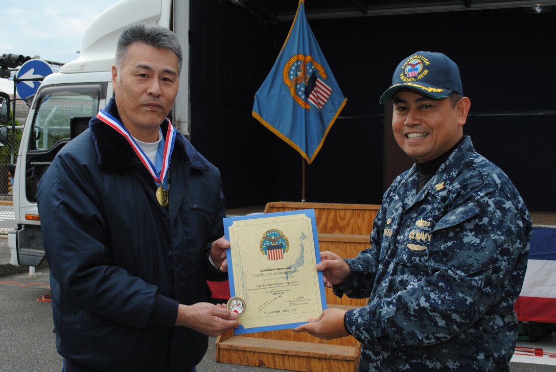 Navy Cmdr. Nolasco Villanueva, commander of DLA Distribution Yokosuka, Japan, presents The Best Individual Performance Award in the Forklift Rodeo to Shigemi Endo from the DLA Distribution Yokosuka Transportation Division.