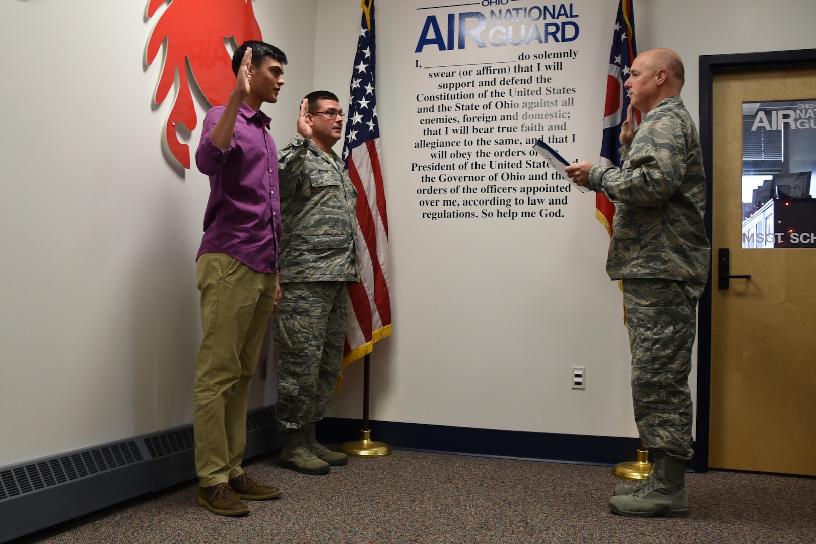 Lt. Col. Philip M. Brown, the 179th Force Support Squadron commander, administers the oath of enlistment Dec. 2, 2016, at the 179th Airlift Wing, Mansfield, Ohio. Cooper Burton is enlisting as his father, Senior Master Sgt. Roger Burton, the fire chief at the 179th AW, is reenlisting. 