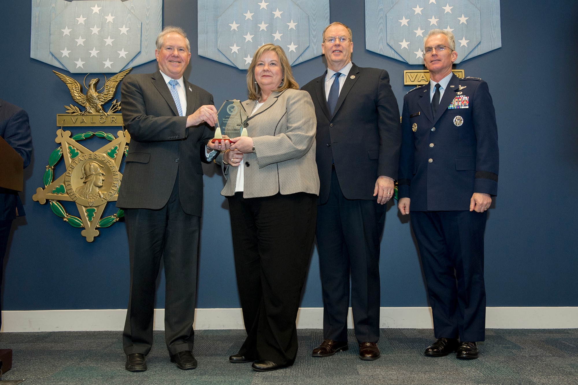 Frank Kendall, Under Secretary of Defense for Acquisition, left, presents Polly McCall with a Defense Acquisition Workforce Individual Award for contracting and procurement during a ceremony at the Pentagon on Dec. 8, 2016. Standing with them are Vice Chairman of the Joint Chiefs of Staff Gen. Paul J. Selva right, and Deputy Secretary of Defense Bob Work. (DoD photo)