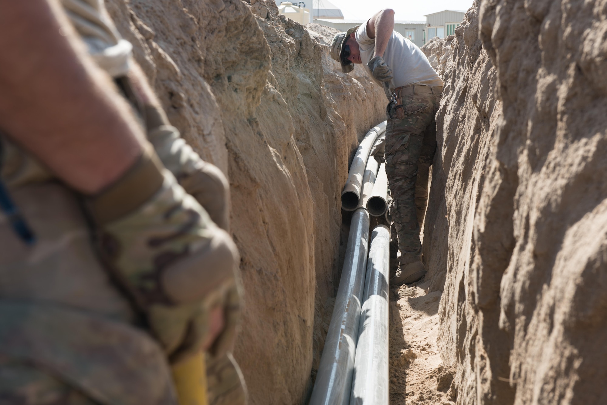 Staff Sgts. Alex Russ, (left) and Sean O’Brien, Engineering and Installation cable and antennae systems technicians, run conduit for communications cables from the 407th Expeditionary Logistics Readiness Squadron compound to the main base at the 407th Air Expeditionary Group, Southwest Asia, Dec. 8, 2016. The engineering and installation team, forward deployed from Headquarters U.S. Air Force Central Command A6, invested more than 550 man-hours, installing over 10,000 feet of conduit.  (U.S. Air Force photo/Master Sgt. Benjamin Wilson)(Released)