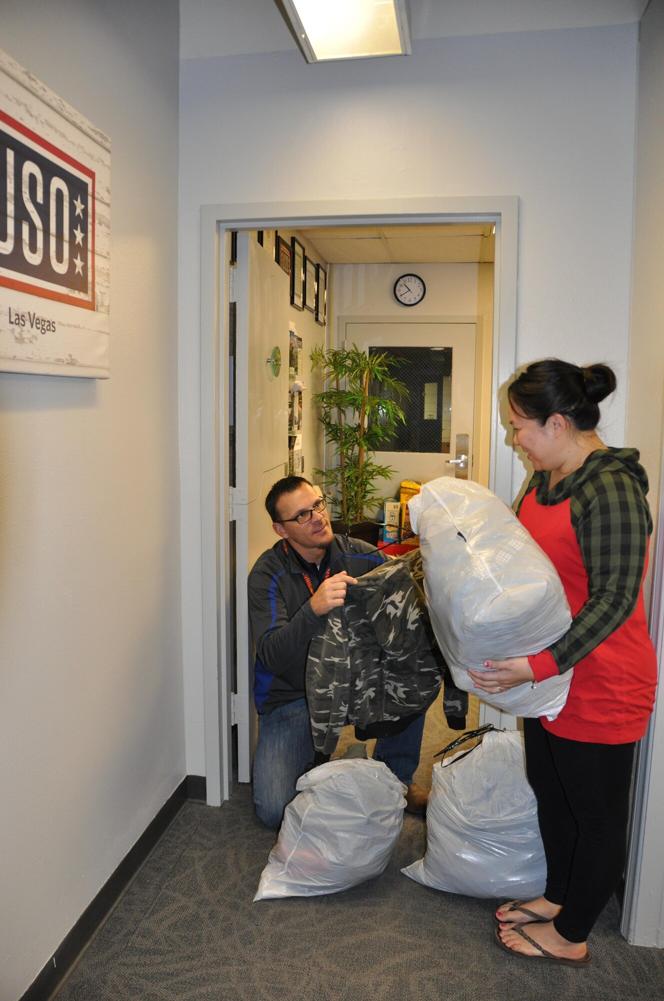 (Left) Clay Barber, Las Vegas USO RP/6 Scout, provides children's clothing to a member in need. The clothes were donated by another Nellis family. The USO provides a range of support to past and present Nellis members, and is also able to connect them with partner programs under the USO Transition 360 Alliance. (U.S. Air Force photo/Maj. Jessica D'Ambrosio)