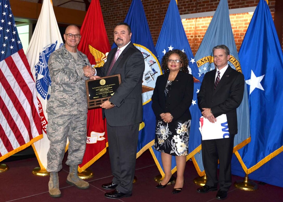 Occupational Safety and Health Administration, Norfolk, Virginia Area Director Stan Dutko, Jr., presents OSHA’s Voluntary Protection Program installation star status plaque flag to Defense Logistics Agency Aviation Commander Air Force Brig. Gen.  Allan Day, Dec. 12, 2016, at Defense Supply Center Richmond. DLA Installation Support Site Director David Gibson holds the VPP Star Worksite flag.  American Federation of Government Employees, Local 1992 President Monique Samuels is also pictured.