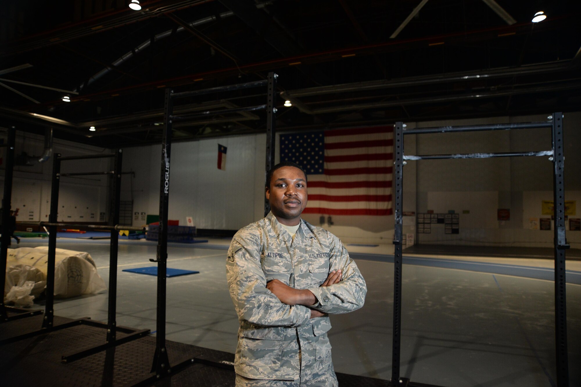 Airman Francis Attipoe, 55th Force Support Squadron, stands proudly in front of an American flag at the fitness center where he works Dec. 14 on Offutt Air Force Base, Neb. Attipoe is from Ghana, Africa, and speaks six different languages. (U.S. Air Force photo by Josh Plueger)