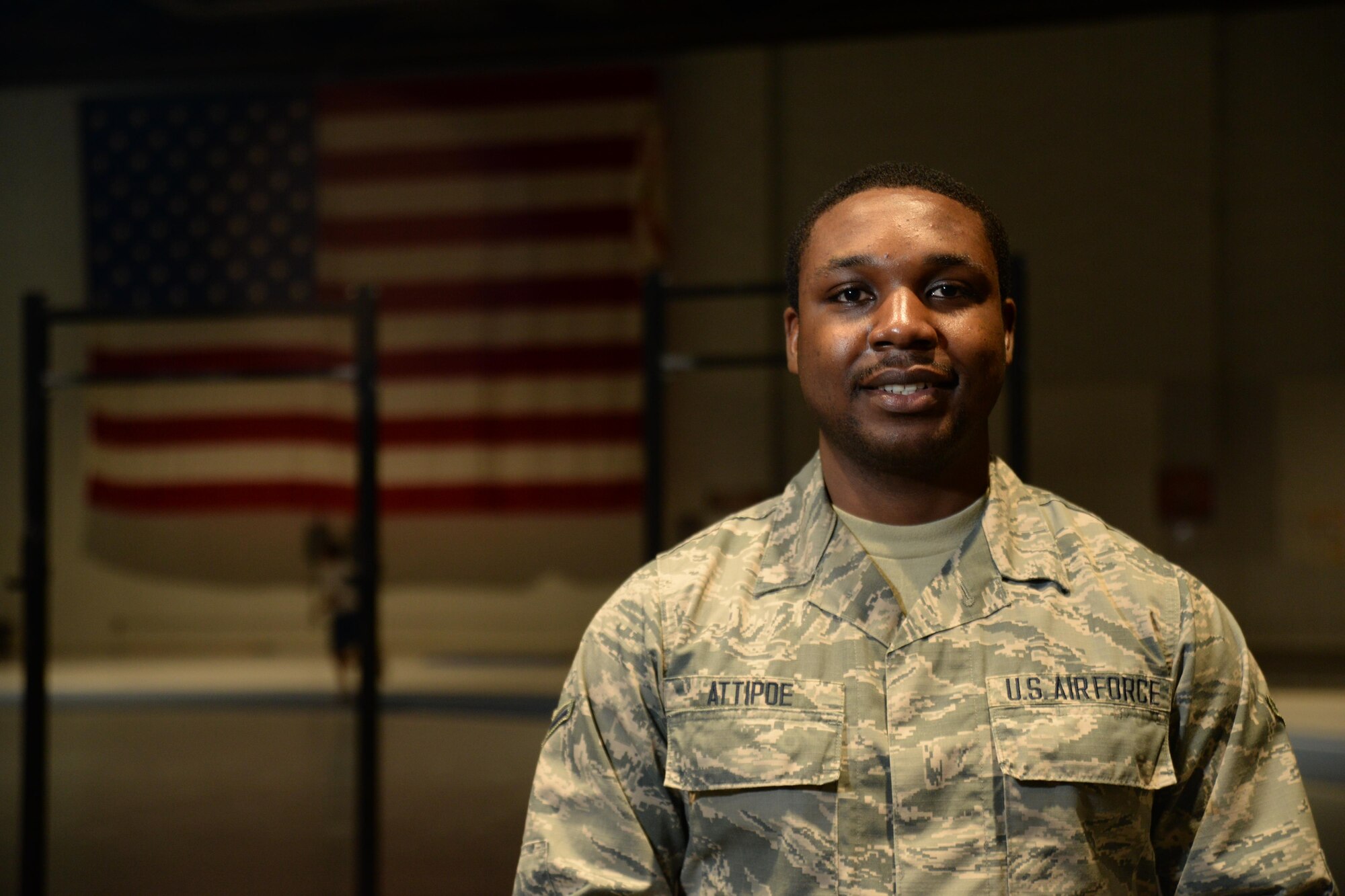 Airman Francis Attipoe, 55th Force Support Squadron, stands proudly in front of an American flag at the fitness center where he works Dec. 14 on Offutt Air Force Base, Neb. Attipoe, from Ghana, Africa, received his U.S. citizenship during basic military training.  (U.S. Air Force photo by Tech. Sgt. Rachelle Blake)