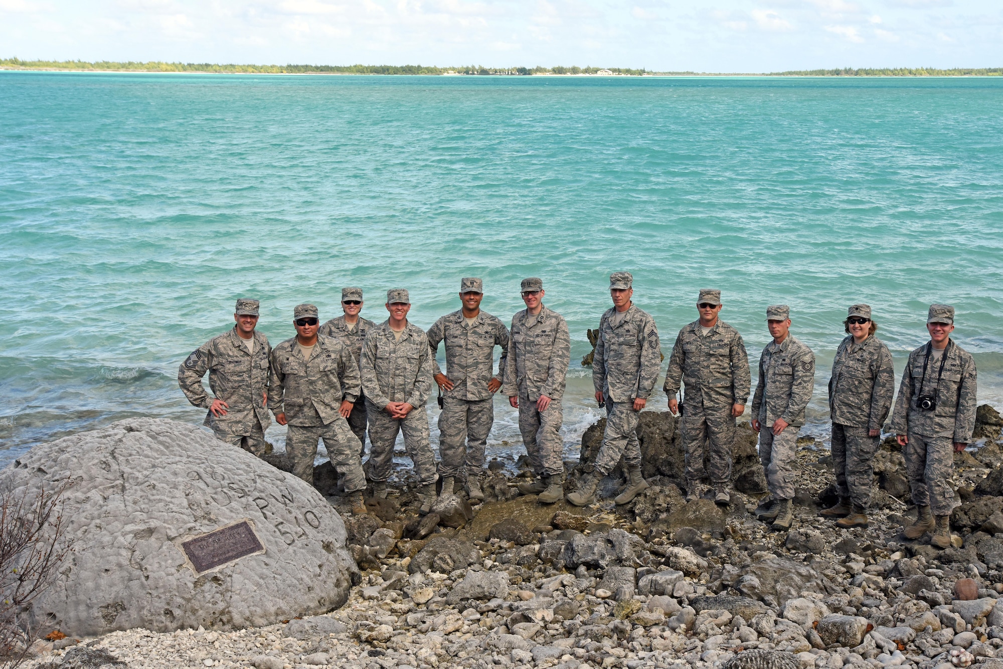 WAKE ISLAND ATOLL--Guests who attended the Battle of Wake Island 75th anniversary ceremony including leadership from Pacific Air Forces Regional Support Center and 11th Air Force pay their respects and pose for a group photo at the "98 Rock Memorial." It is said that one of the 98 civilian prisoners of war etched a message into the rock; "98 U.S. P.W. 5-10-43." The 98 civilians were executed Oct. 7, 1943 by Japanese forces who controlled the island after the Battle for Wake Island in December 1941. (U.S. Air Force photo/Tech. Sgt. John Gordinier)