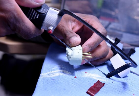 Staff Sgt. Khodie Morgan, 341st Medical Operations Squadron dental laboratory technician, sections a cast into dies for a gold crown using a hand saw in the dental laboratory Dec. 5, 2016, at Malmstrom Air Force Base, Mont. The die is the reproduction of the tooth consisting of a hard substance like metal, stone or resin. (U.S. Air Force photo/Senior Airman Jaeda Tookes)