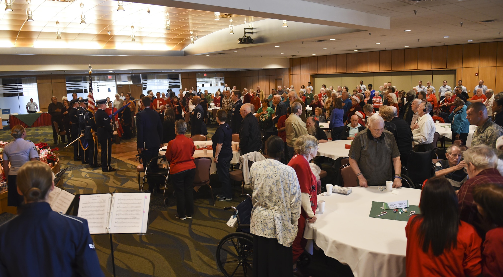 Attendees at the 30th Annual Golden Age Holiday Party stand for the posting of the colors and singing of the National Anthem at the Horizons Community Center at Tyndall Air Force Base, Fla., Dec. 15, 2016. More than 200 local senior citizens attended the event.  (U.S. Air Force photo by Senior Airman Dustin Mullen/Released)