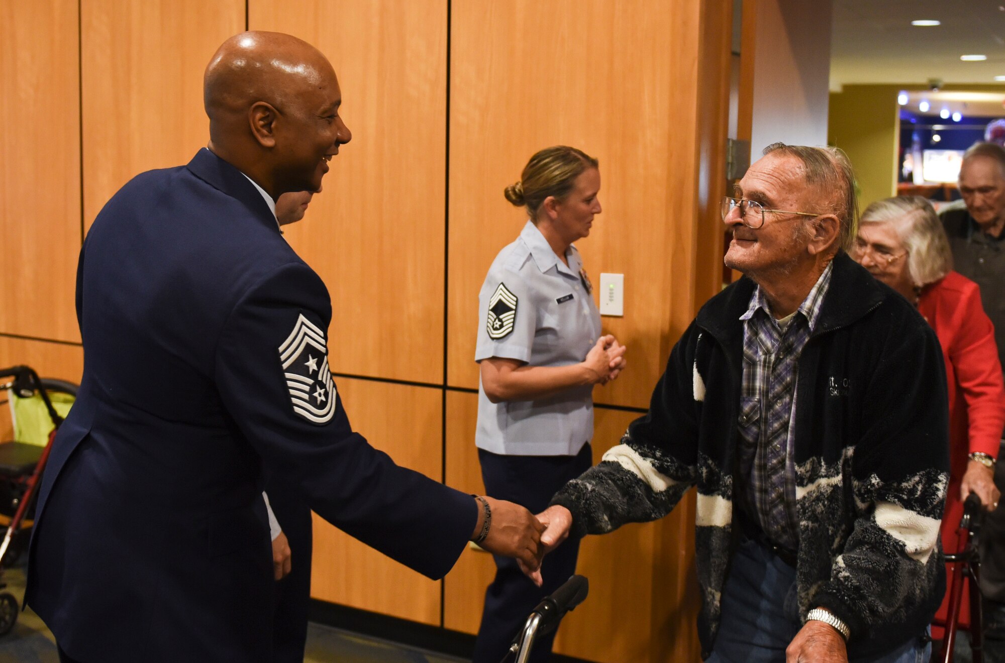 U.S. Air Force Chief Master Sgt. Craig Williams, 325th Fighter Wing command chief, shakes the hand of Mr. Jerry Clift, a local senior citizen and U.S. Army veteran, as he enters the 30th Annual Golden Age Holiday Party at Horizons Community Center at Tyndall Air Force Base, Fla., Dec. 15, 2016. During the event, volunteers handed out more than 200 gifts and 200 fruit baskets. (U.S. Air Force photo by Senior Airman Dustin Mullen/Released)