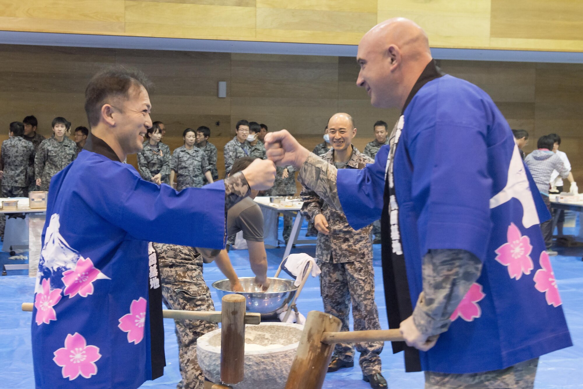 Chief Master Sgt. Christopher Yevchak, 374th Airlift Wing command chief, bumps fists in celebration with a member of the Japan Air Self-Defense Force after pounding mochi at Yokota Air Base, Japan, Dec. 14, 2016. Mochitsuki, or rice pounding, is a ceremony held in preparation for New Year celebration. (U.S. Air Force photo by Senior Airman David C. Danford/Released)