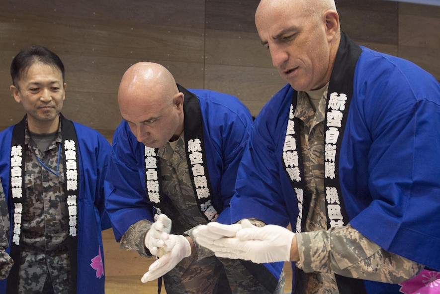 (right) Col. Kenneth Moss, 374th Airlift Wing commander, and Chief Master Sgt. Christopher Yevchak, 374 AW command chief, roll mochi during a traditional Japanese event hosted by the Japan Air Self-Defense Force at Yokota Air Base, Japan, Dec. 14, 2016. Sweets, sugars or toasted soy bean powder are often added to mochi before eating. (U.S. Air Force photo by Senior Airman David C. Danford/Released)