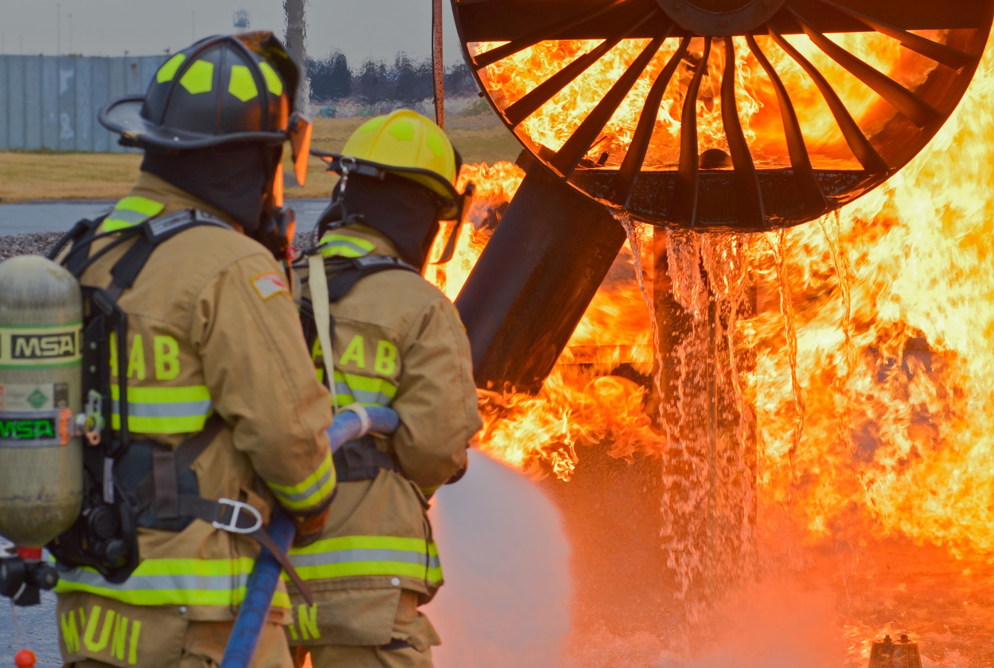 Two firefighters with the 374th Civil Engineer Squadron put out a simulated aircraft fire during a training scenario at Yokota Air Base, Japan, Dec. 14, 2016. During the training the firefighters were split into three teams of two, with two teams extinguishing the fires and the remaining team on standby providing a safety line to help the primary teams. (U.S. Air Force photo by Staff Sgt. David Owsianka)