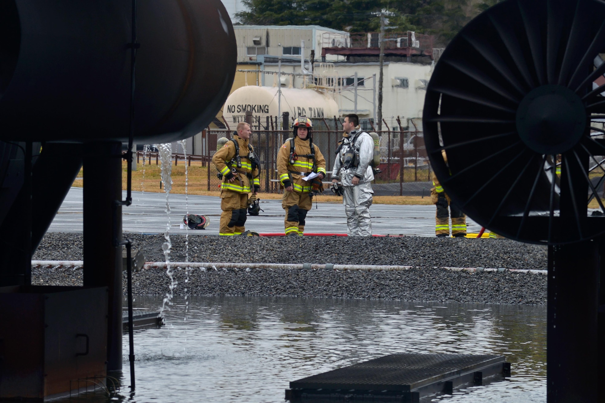 Firefighters with the 374th Civil Engineer Squadron discuss the previous training scenario at Yokota Air Base, Japan, Dec. 14, 2016. The training consisted of a training aircraft burning with two engine fires with leaking fuel spreading on the ground to simulate an aircraft on the runway needing assistance. (U.S. Air Force photo by Staff Sgt. David Owsianka)