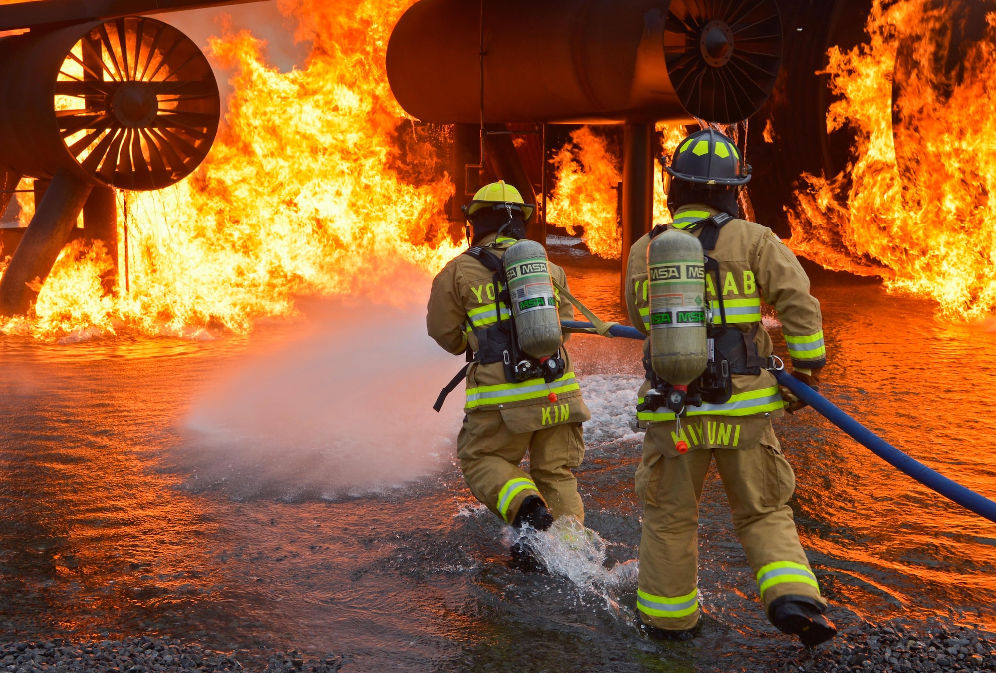 Two firefighters with the 374th Civil Engineer Squadron move towards a simulated aircraft fire during a training scenario at Yokota Air Base, Japan, Dec. 14, 2016. The training helped the firefighters gain experience and build cohesiveness to work as a better team for potential real-world scenarios. (U.S. Air Force photo by Staff Sgt. David Owsianka)