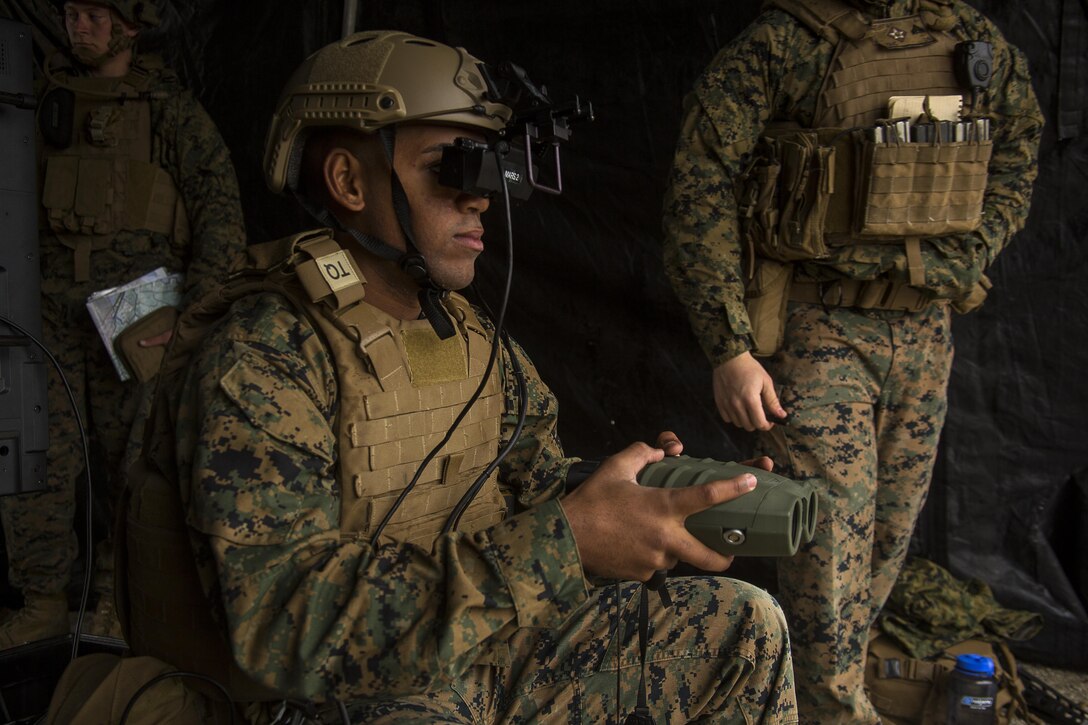 Lance Cpl. Jorge Brito uses the Augmented Immersive Team Trainer to call in mortar fire on virtual targets at Camp Lejeune, N.C., Dec. 13, 2016. Brito is holding a Target Hand-Off System integrated with the AITT to spot out virtual tanks while getting coordinates to call in mortar fire. Brito is a fire support Marine with 2nd Battalion, 10th Marine Regiment, 2nd Marine Division. (U.S Marine Corps photo by Lance Cpl. Juan A. Soto-Delgado)