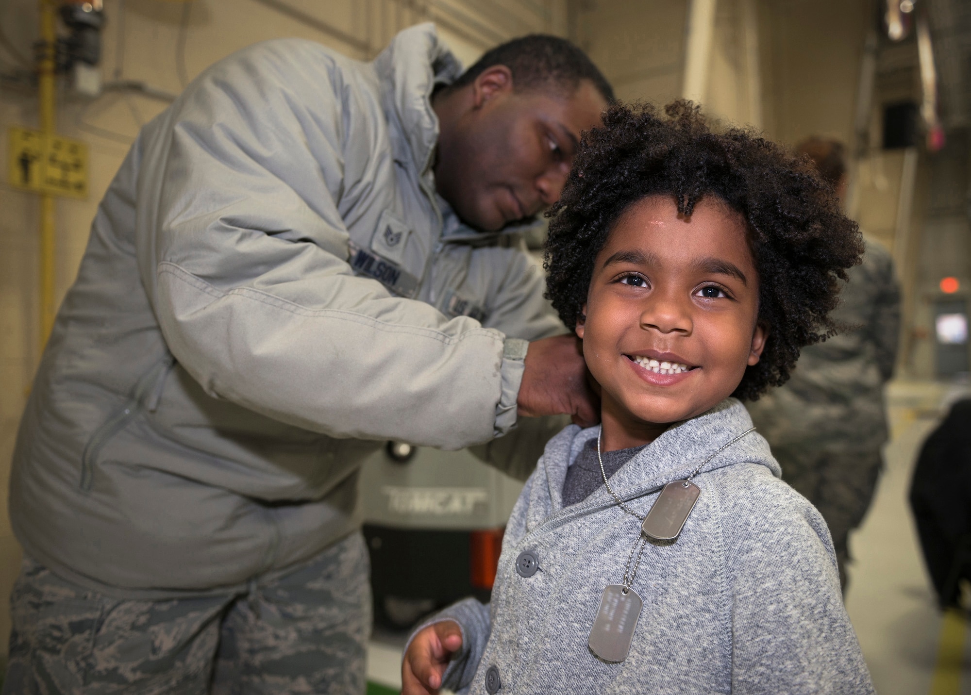 U.S. Air Force Staff Sgt. Cameron Wilson, a public health craftsman with the 182nd Medical Group, Illinois Air National Guard, places personalized dog tags on his son at the 182nd Airlift Wing’s annual holiday party Dec. 3 in Peoria, Ill. The Peoria Vet Center gifted the dog tags to unit members' children at the party. (U.S. Air National Guard photo by Tech. Sgt. Lealan Buehrer) (Dog tags identification digitally obscured per policy.)
