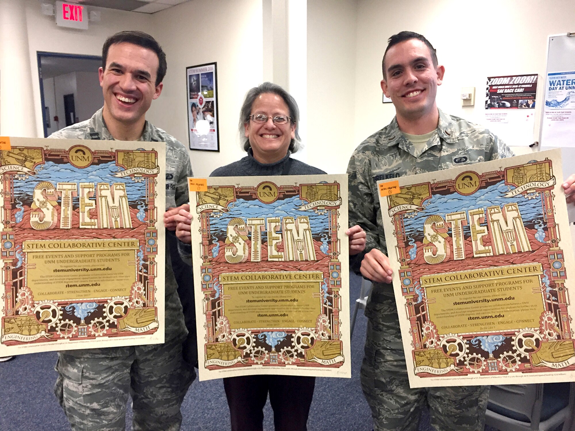 Air Force Research Laboratory mentors, from left, Capt. Timothy Wolfe, Imelda Atencio and 2nd Lt. Evan Threlkeld hold posters announcing the University of New Mexico STEM Collaborative Center during a visit to that center. The mentoring program matches UNM undergraduate students with AFRL scientists and engineers, military or civilian, to provide personal and professional mentorship.