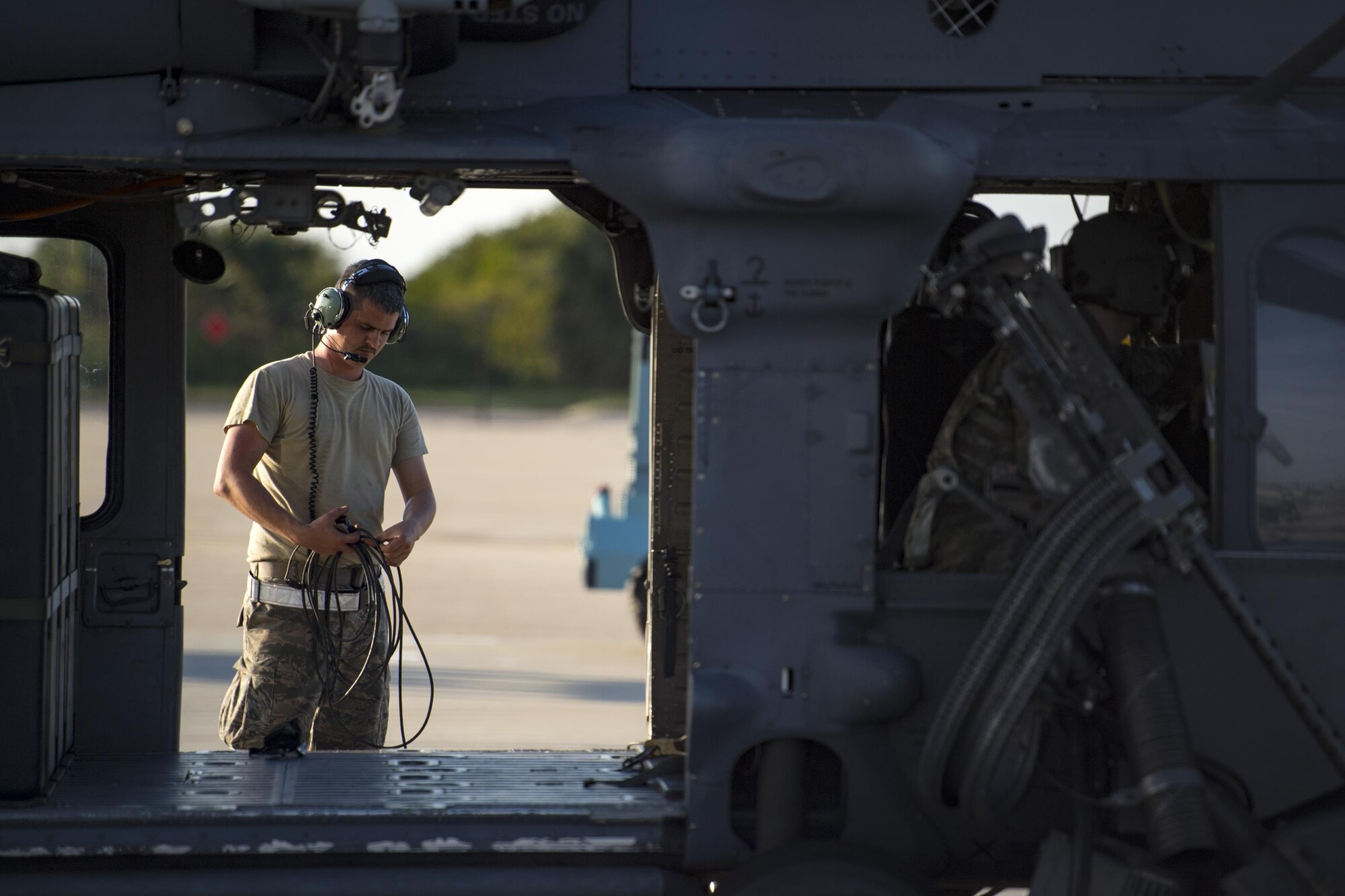 An Airman from the 41st Helicopter Maintenance Unit coils a headset cord while aircrew members from the 41st Rescue Squadron prepare for a mission in an HH-60G Pave Hawk, Dec. 12, 2016, at Patrick Air Force Base, Fla. The 41st HMU worked alongside the 41st Rescue Squadron for ten days as they conducted pre-deployment “spin-up” training. The maintainers were responsible for ensuring three aircraft were combat-ready at a moment’s notice and worked around the clock to meet this requirement for both day and night missions. (U.S. Air Force photo by Staff Sgt. Ryan Callaghan)