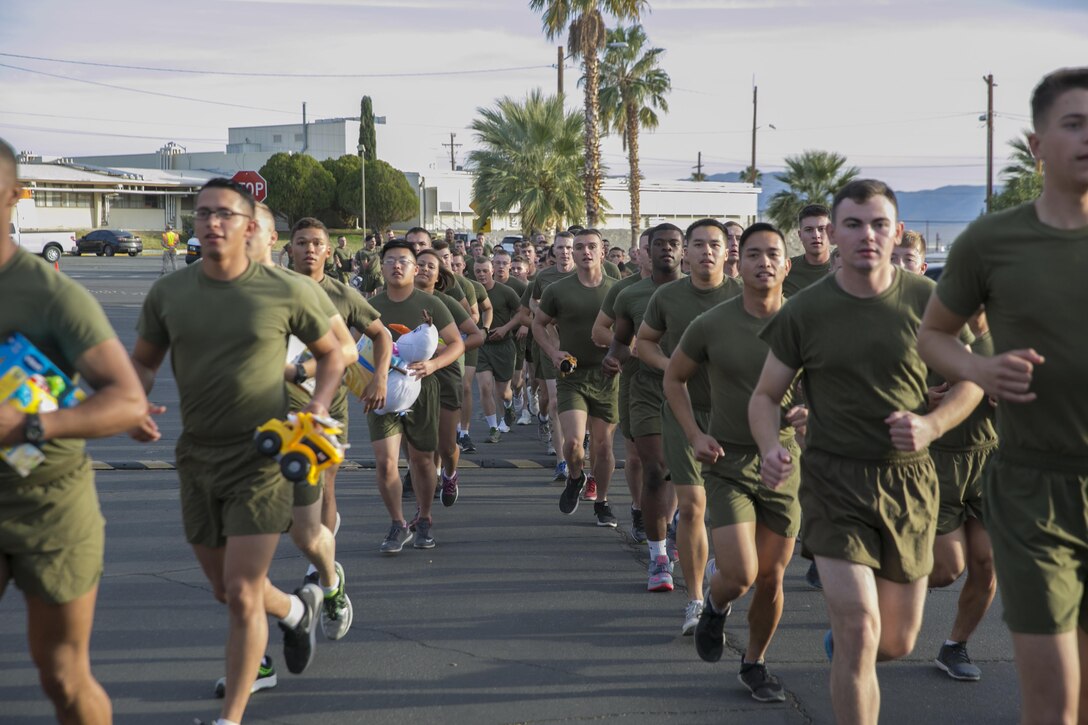 Students and staff of Marine Corps Communication-Electronics School carry toys to donation bins during the Toys for Tots Fun Run aboard Marine Corps Air Ground Combat Center, Twentynine Palms, Calif., Dec. 14, 2016. (Official Marine Corps photo by Lance Cpl. Dave Flores/Released)
