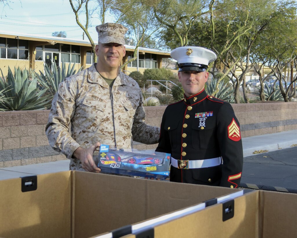 Brig. Gen. William F. Mullen III, Combat Center Commanding General, gives Sgt. Joshua Ulrich, radar maintenance chief, Marine Corps Communication-Electronics School, the first gift for donation during the Toys for Tots Fun Run aboard Marine Corps Air Ground Combat Center, Twentynine Palms, Calif., Dec. 14, 2016. (Courtesy photo by Kathleen Arbaczewski/Released)
