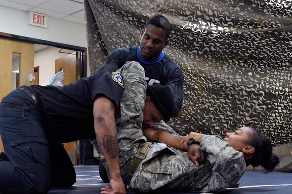 Senior Airman Jexsira Watts, a 633rd Security Forces Squadron response force leader, applies a triangle choke on Tony Molette, a 633rd SFS law enforcement officer, with assistance from Lorenz Larkin, a professional Ultimate Fighting Championship mixed martial artist, during a combatives course at Joint Base Langley-Eustis, Va., Dec. 8, 2016. Larkin’s appearance was part of a distinguished visitor tour where military members and dependents had an opportunity to meet and get autographs from UFC fighters and radio hosts. (U.S. Air Force photo/Staff Sgt. Nick Wilson)