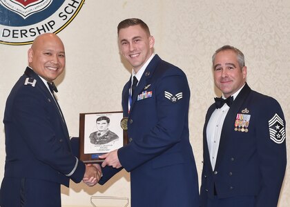 U.S. Air force Col. Jimmy Canlas, 437th Airlift Wing commander, left, with Chief Master Sgt. Kristopher Berg, 437th Airlift Wing command chief, right, congratulate Senior Airman Drew Gayhart, 16th Airlift Squadron, for receiving the John L. Levitow Award during an Airman Leadership School Graduation ceremony Dec. 15, 2016, at Joint Base Charleston, South Carolina. The Levitow Award is the highest honor bestowed during ALS and is awarded to the Airman who displays the highest level of leadership qualities.