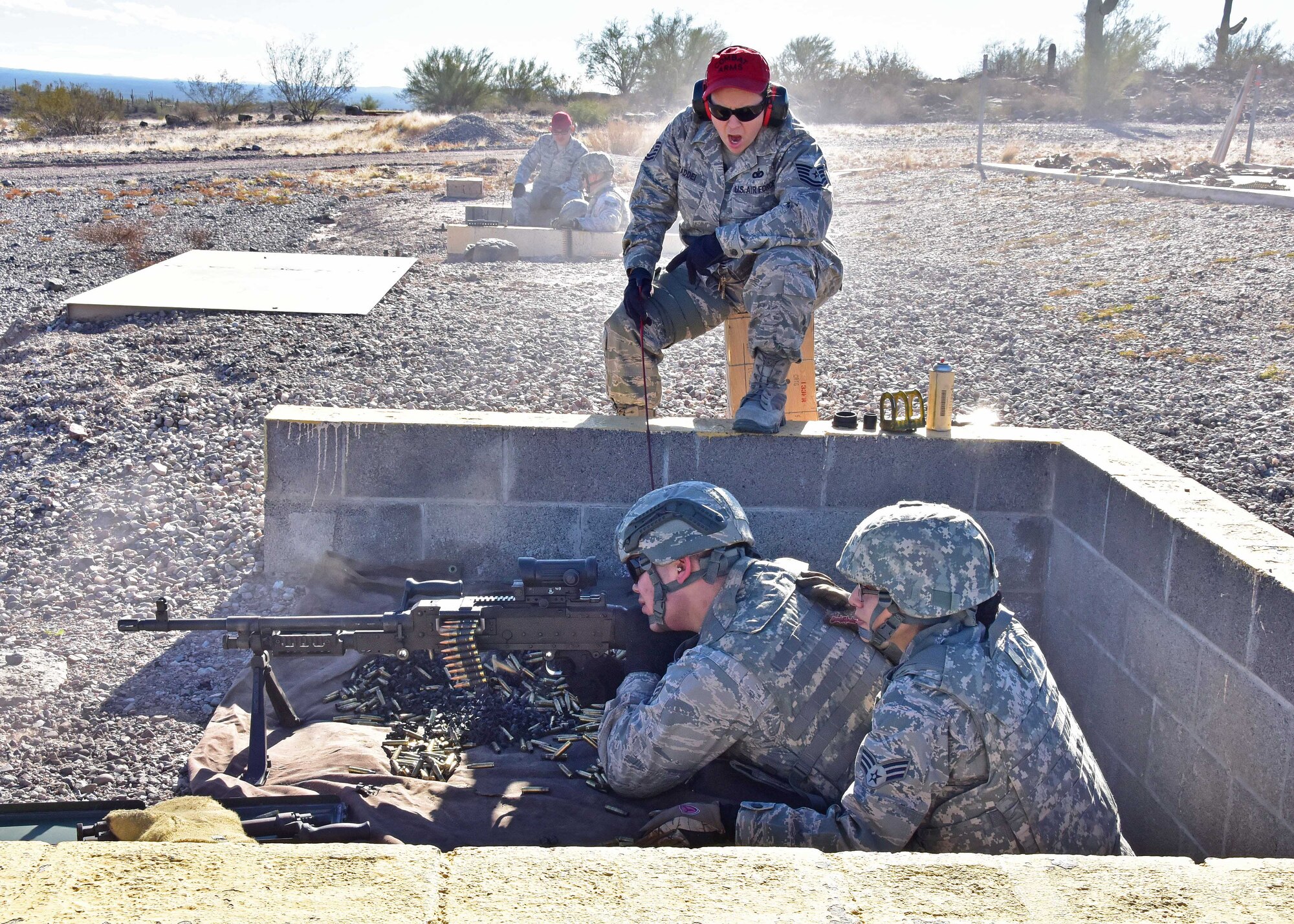 Tech. Sgt. Leah Taddei, 944th Security Forces combat arms training and maintenance instructor, directs Senior Airman Antonio Duarte, fire team member, as he fires the M240B Dec. 3 at the Army National Guard range in Florence, Ariz. Senior Airman Dominique Castillo, fire team member, guides and informs Duarte of the vicinity of his rounds. This was part of their yearly heavy weapons qualifications. (U.S. Air Force photo taken by Tech. Sgt. Louis Vega Jr.)